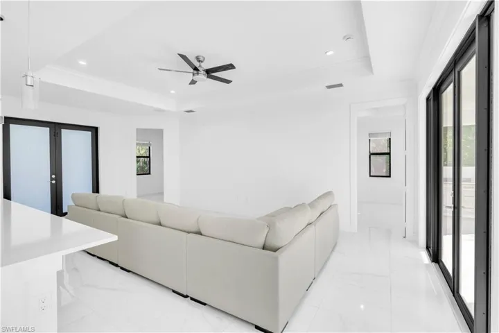 Living area featuring recessed lighting, light marble finish floors, and ornamental molding