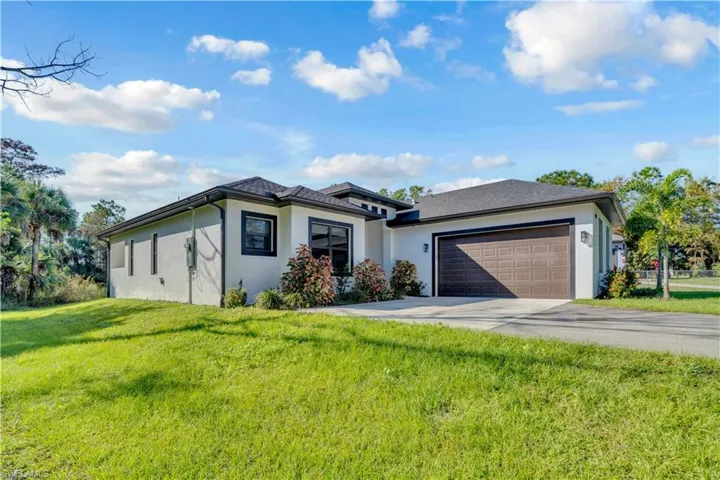 Prairie-style house featuring stucco siding, a front lawn, concrete driveway, and an attached garage
