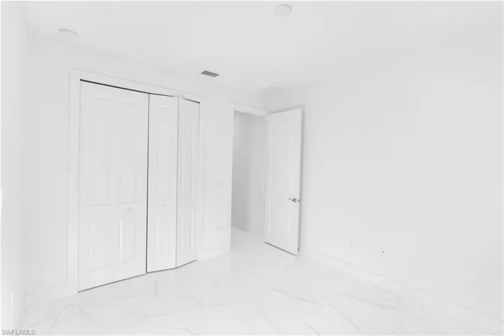 Unfurnished bedroom with light marble finish floors and a closet
