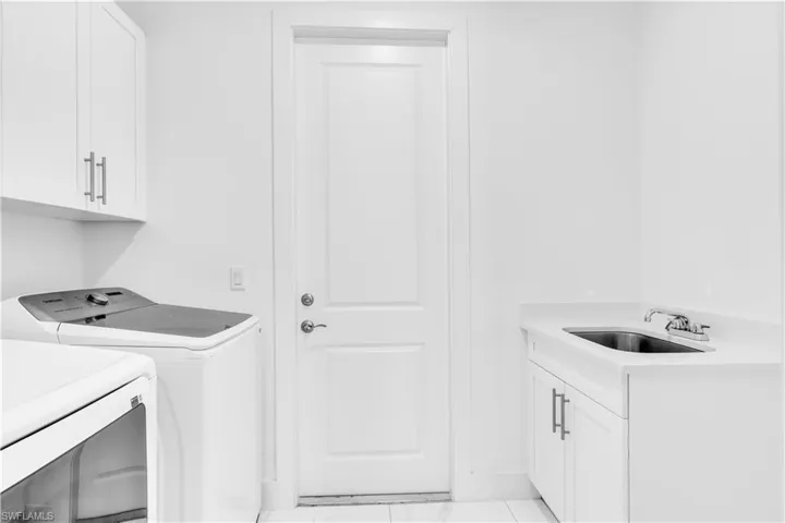 Washroom featuring cabinet space, washing machine and clothes dryer, and light marble finish floors
