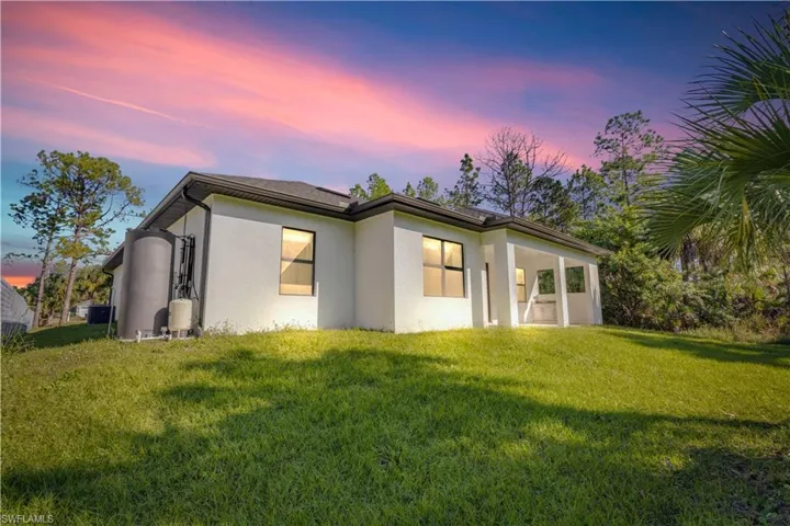 Back of house featuring stucco siding, a lawn, and a patio area
