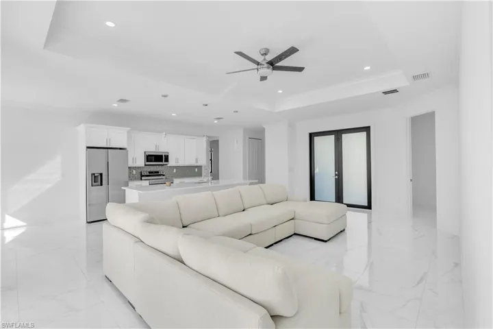 Living room featuring crown molding, recessed lighting, light marble finish flooring, french doors, and ceiling fan