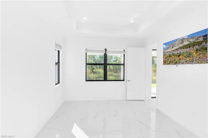 Empty room featuring light marble finish flooring, a tray ceiling, crown molding, and recessed lighting