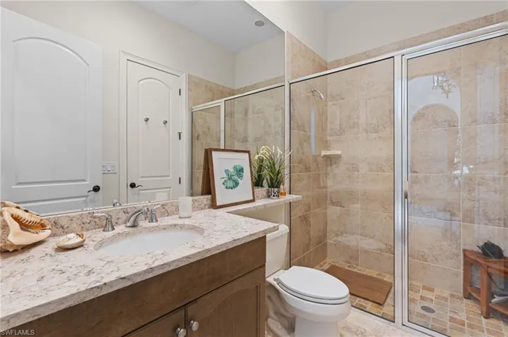 Bathroom with vanity, toilet, and a shower with shower door