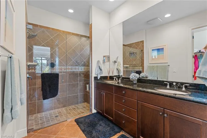 Bathroom featuring a tile shower, vanity, and tile patterned floors