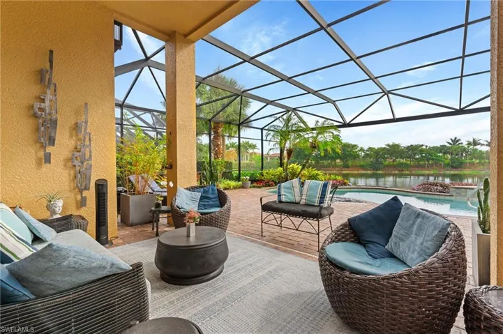 View of patio featuring glass enclosure, a water view, and an outdoor hangout area