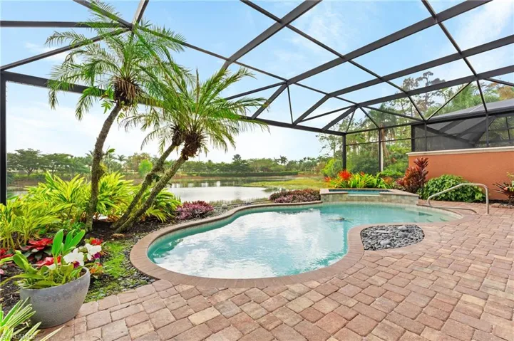 View of pool featuring an in ground hot tub, a water view, a patio area, and a lanai