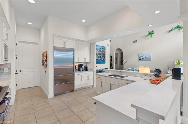 Kitchen with decorative backsplash, stainless steel appliances, sink, light tile patterned floors, and white cabinetry