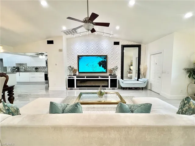 Spacious living area featuring a vaulted ceiling with a ceiling fan, recessed lighting, and large format tile flooring