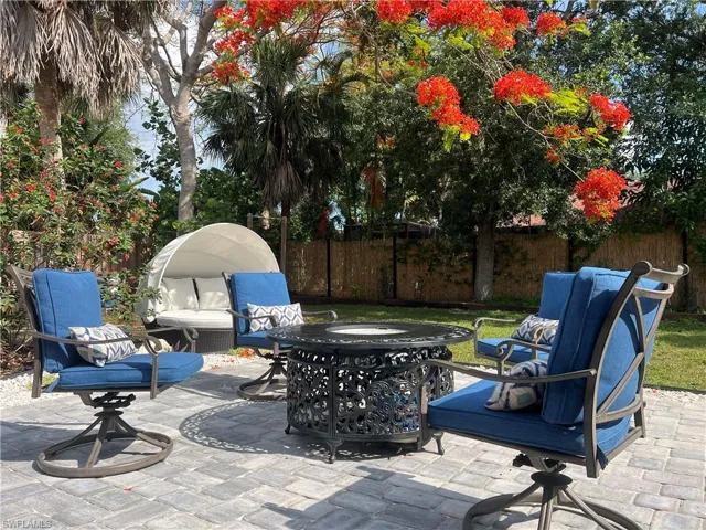 Paver patio featuring mature tropical landscaping and a vibrant flowering tree