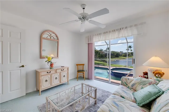 Living room with a water view, a ceiling fan, and carpet flooring