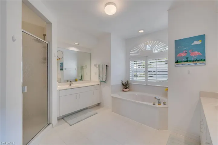 Bathroom featuring two vanities, a stall shower, a garden tub, recessed lighting, and light tile patterned floors