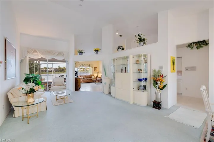 Sitting room featuring a water view, a towering ceiling, and carpet flooring