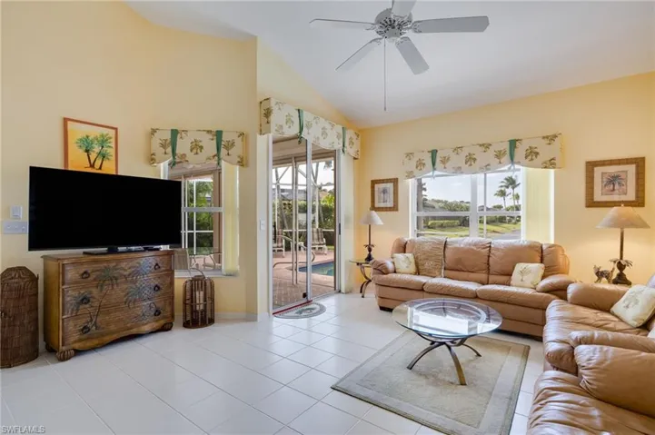 Living room with vaulted ceiling, tile patterned flooring, and a ceiling fan