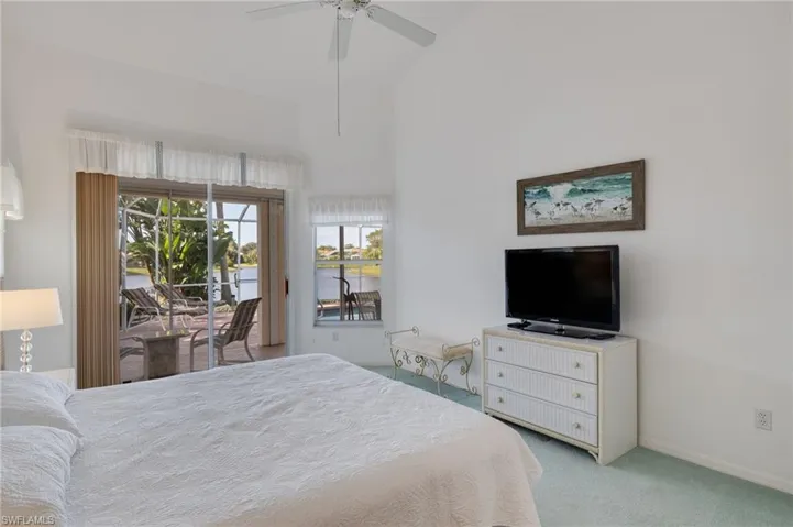 Bedroom featuring access to outside, light carpet, a high ceiling, and a ceiling fan