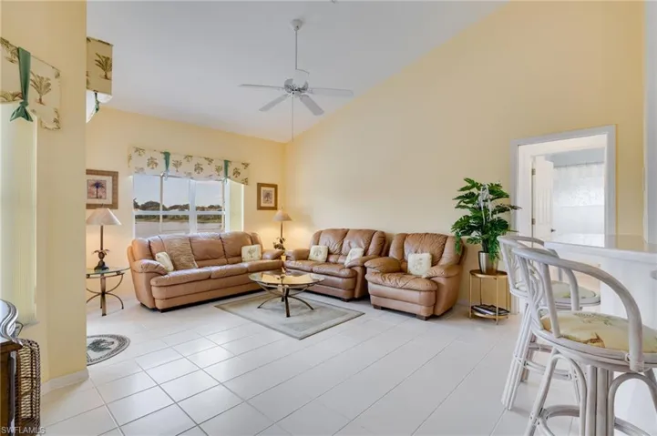 Living area featuring high vaulted ceiling, light tile patterned floors, and ceiling fan