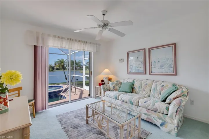 Living room with a water view, carpet flooring, and ceiling fan