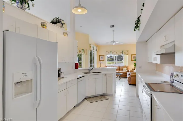 Kitchen featuring white appliances, light countertops, a peninsula, and white cabinets