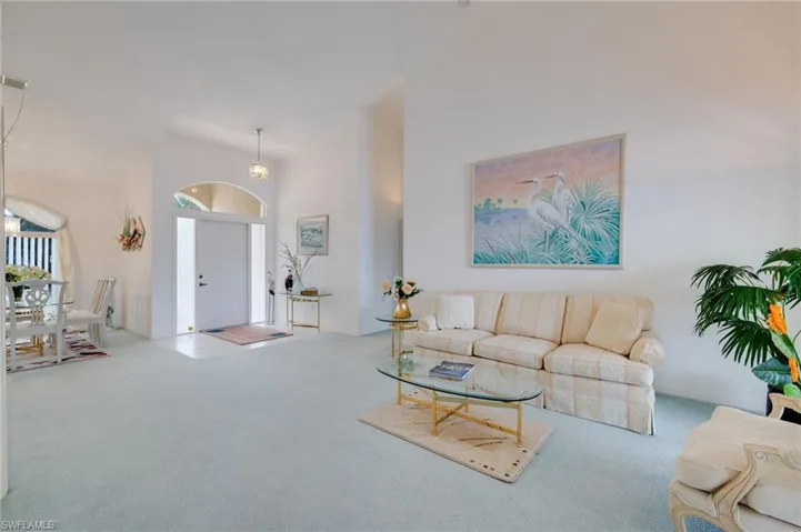 Living room with carpet flooring and high vaulted ceiling