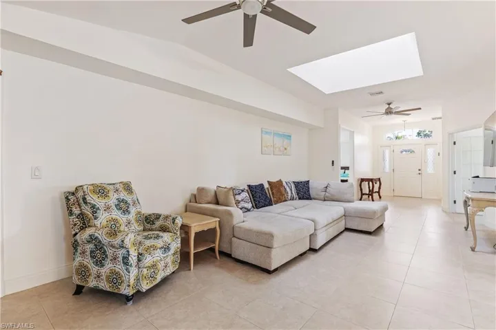 Living room featuring ceiling fan, light tile patterned floors, and a skylight