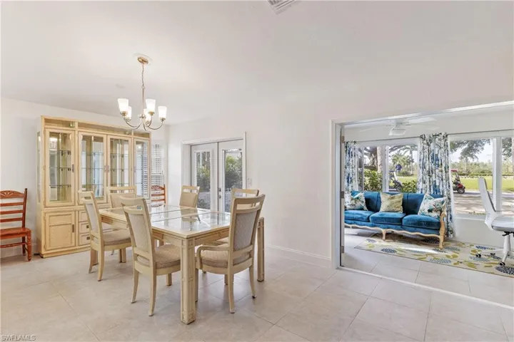 Tiled dining area featuring french doors and ceiling fan with notable chandelier