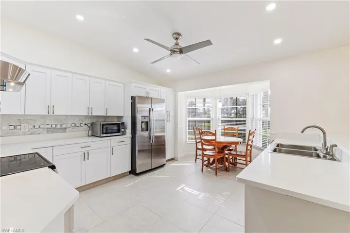 Updated Kitchen featuring ceiling fan, white cabinetry, and stainless steel appliances, and quartz counters