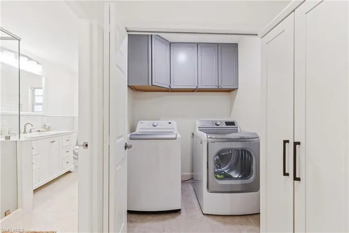 Laundry area with light tile patterned floors, sink, separate washer and dryer, and cabinets