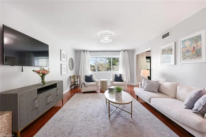 Living room with dark wood-style flooring, visible vents, and baseboards