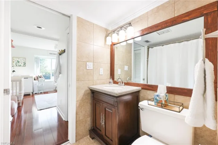 Bathroom with visible vents, wood finished floors, tile walls, and vanity
