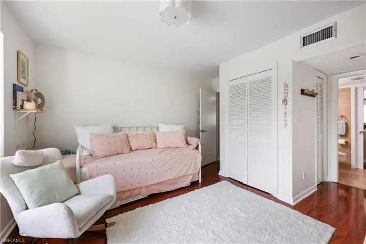 Bedroom with dark wood-style floors, a closet, visible vents, and baseboards