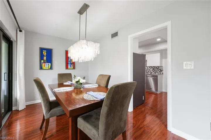 Dining room with dark wood-style floors, baseboards, visible vents, and a chandelier