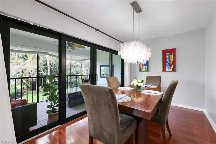 Dining room featuring an inviting chandelier, baseboards, and dark wood-style flooring