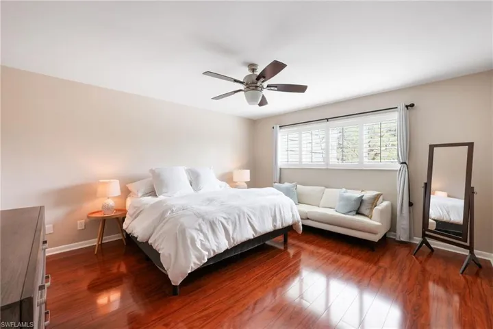 Bedroom with dark wood-style flooring, ceiling fan, and baseboards