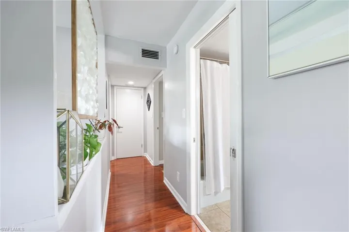 Hall featuring wood finished floors, visible vents, and baseboards