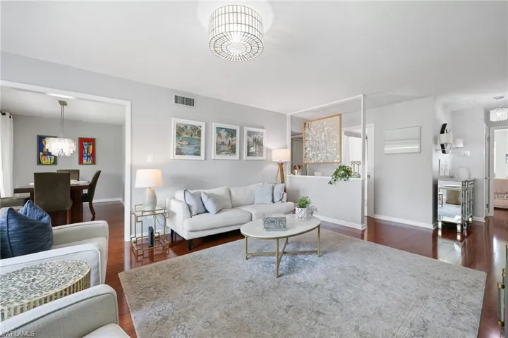 Living area featuring baseboards, visible vents, a chandelier, and dark wood-style flooring