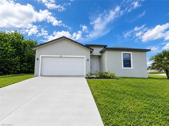 Exterior featuring a light-colored stucco finish, attached two-car garage, and a concrete driveway