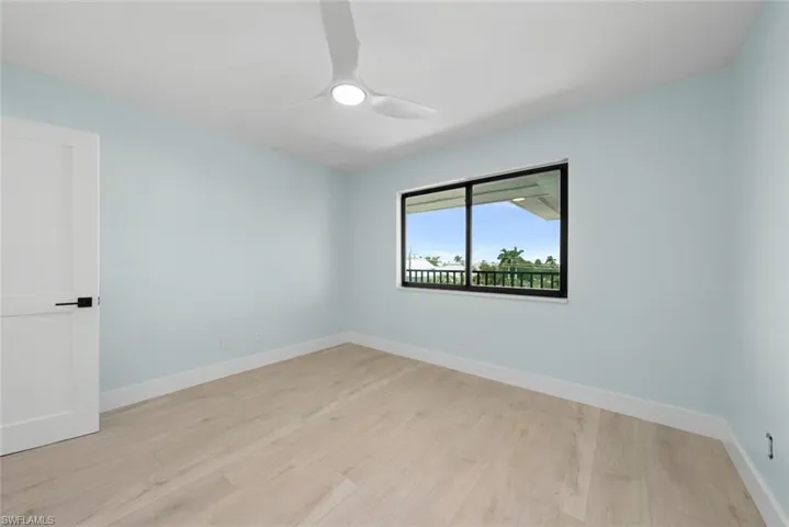 This room features light-toned flooring, light blue walls, and a modern ceiling fan