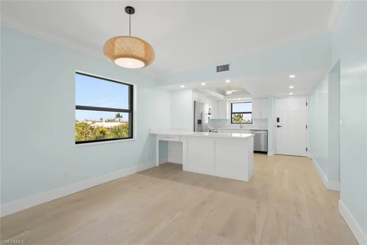 This open concept living space features light-colored flooring, light blue walls, and a contemporary light fixture