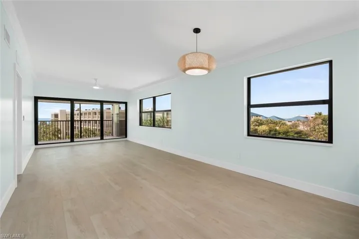 Spacious room featuring light-toned flooring, light blue walls, and a contemporary light fixture