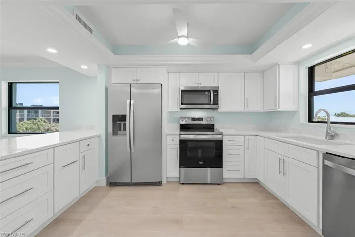 The kitchen features white cabinetry, stainless steel appliances, and light-colored flooring
