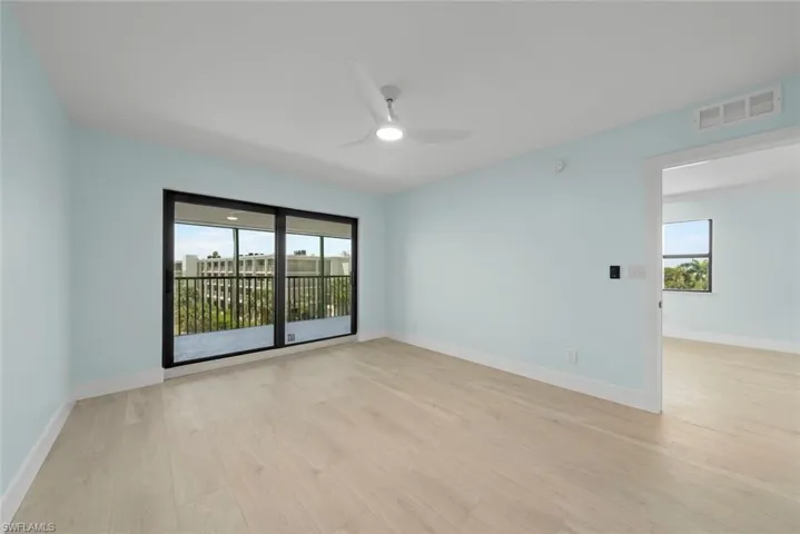 This room features light wood-style flooring and light blue walls, complemented by a ceiling fan