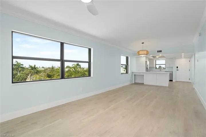 Expansive living area with light-toned flooring, offering views of verdant trees through large windows