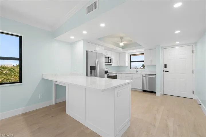 The kitchen features white cabinetry, stainless steel appliances, and a light-colored countertop