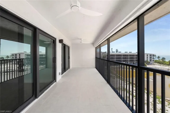 Expansive balcony with durable tile flooring and a black railing, offering open sky views and glimpses of the water