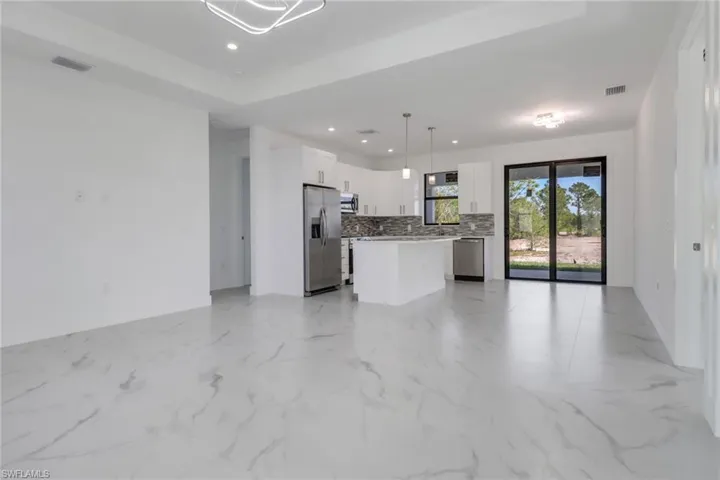 Kitchen featuring stainless steel appliances, pendant lighting, backsplash, a center island, and white cabinetry