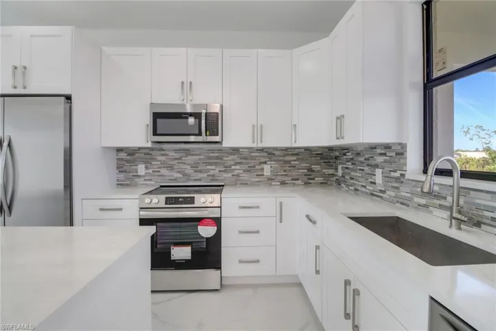 Kitchen with sink, stainless steel appliances, white cabinets, and backsplash