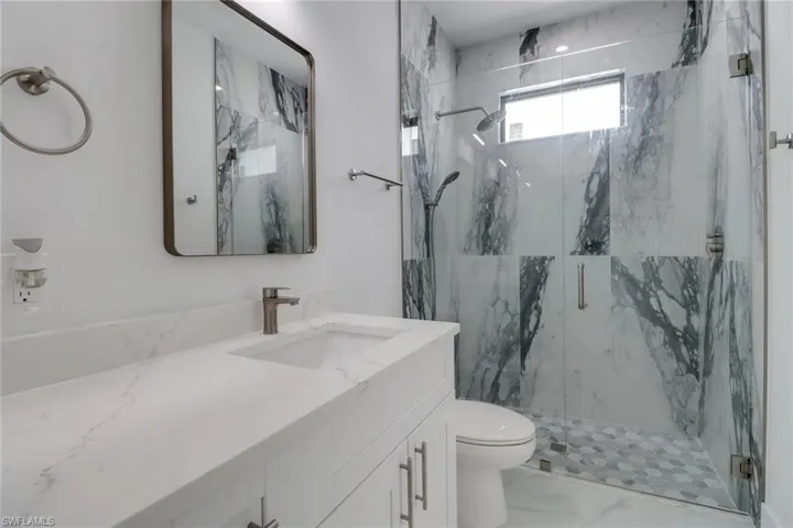 Bathroom featuring toilet, vanity, and walk in shower