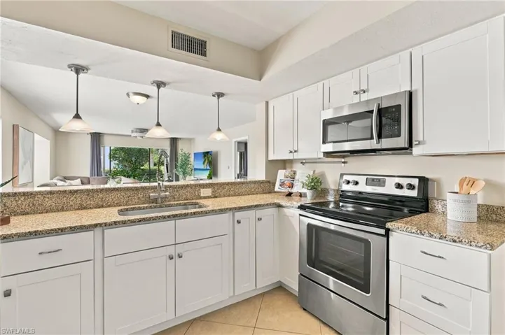 Kitchen featuring white cabinetry, stone-finish countertops, stainless steel appliances, and pendant lighting