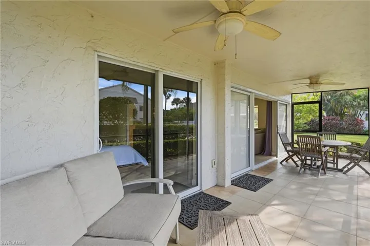 Covered patio featuring ceramic tile flooring, dual ceiling fans with integrated lighting, and multiple sliding glass door entries enclosed by mesh screening