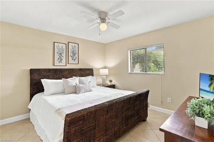 Neutral-toned room with tile flooring, a central ceiling fan with an integrated light fixture, and a window fitted with horizontal blinds